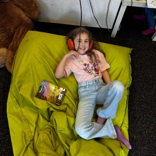 Ein Kind hört sich eine Toniboxgeschichte an und liegt auf einem Sitzsack.