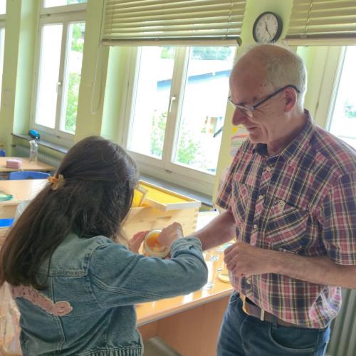 Der Imker zeigt den Kindern Bienenprodukte.