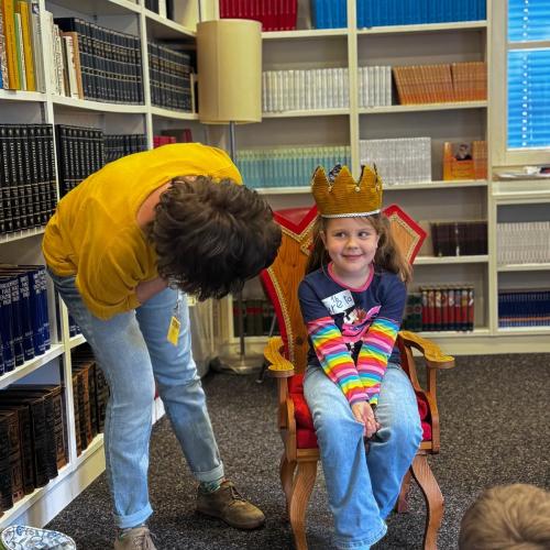 Ein Kind wird zur Lesekönigin gekrönt von einer Büchereimitarbeiterin.