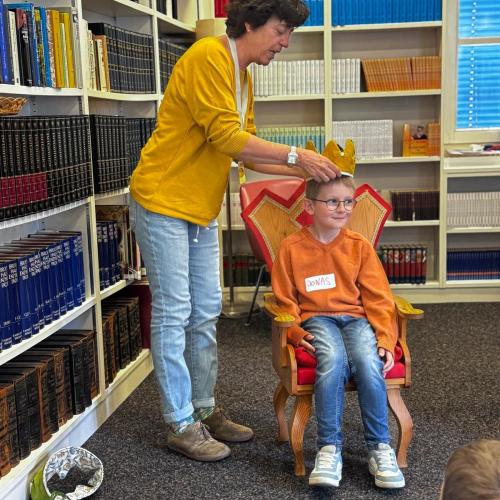 Ein Kind wird zur Lesekönigin gekrönt von einer Büchereimitarbeiterin.