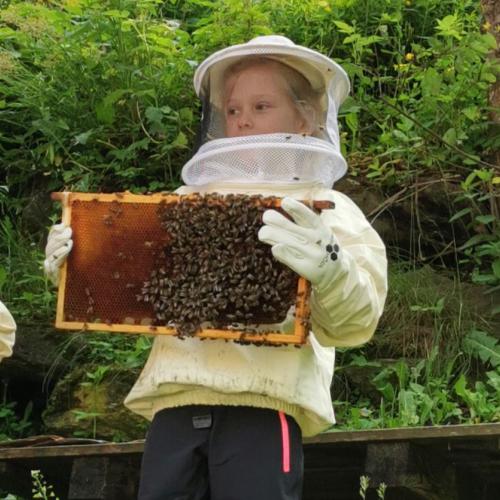 Kind in Imkerkleidung mit Gitterrahmen