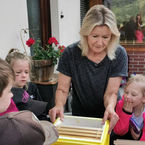 Imkerin zeigt Kindern Gitterböden 