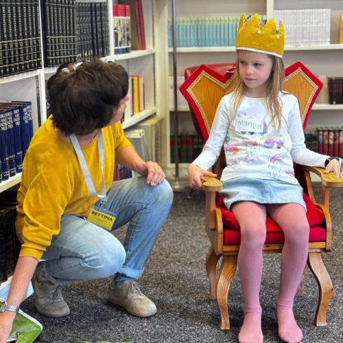 Ein Kind wird zur Lesekönigin gekrönt von einer Büchereimitarbeiterin.