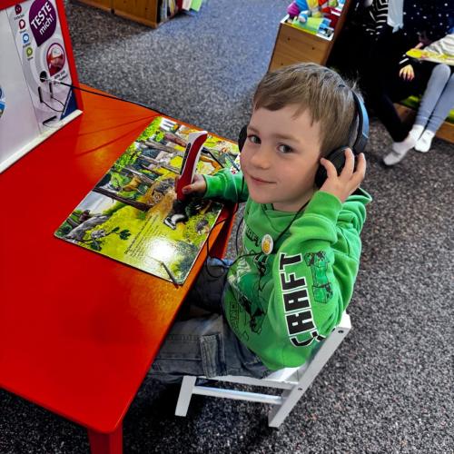 Ein Kind arbeitet mit einem Tiptoistift in einem Buch.