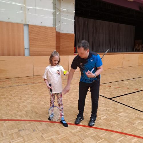 Der Tennislehrer erklärt einem Kind die richtige Haltung des Tennisschlägers.