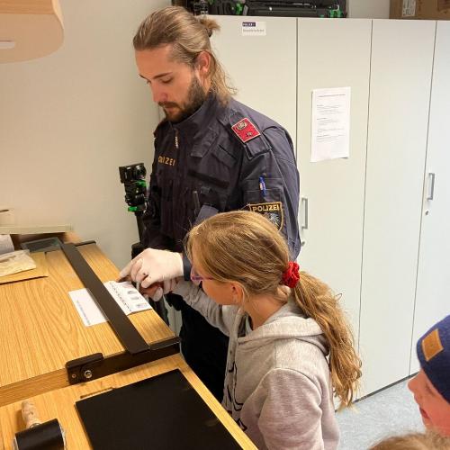 Ein Polizist zeigt den Kindern, wie man Fingerabdrücke nimmt.