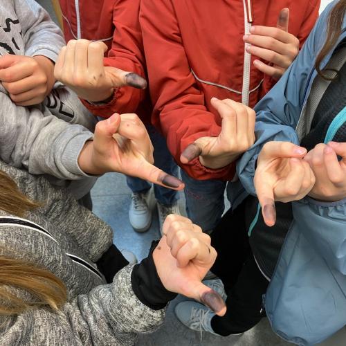 Die Kinder zeigen ihre geschwärzten Daumen vom Fingerabdrucknehmen.