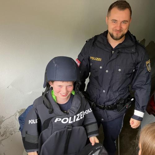 Ein Kind zieht eine Polizeiweste an.
