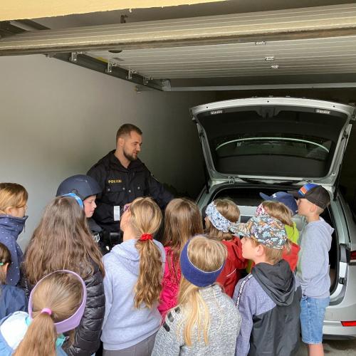 Ein Polizist erklärt den Kindern, was alles in einem Polizeiauto ist und zeigt es ihnen.