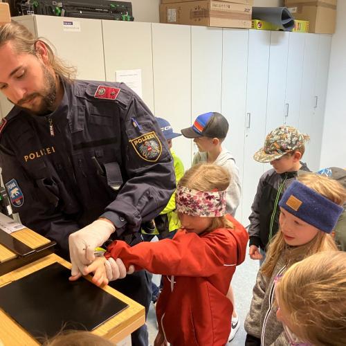 Ein Polizist zeigt den Kindern, wie man Fingerabdrücke nimmt.