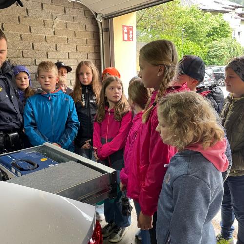 Ein Polizist erklärt den Kindern die Ausrüstung des Streifenwagens.