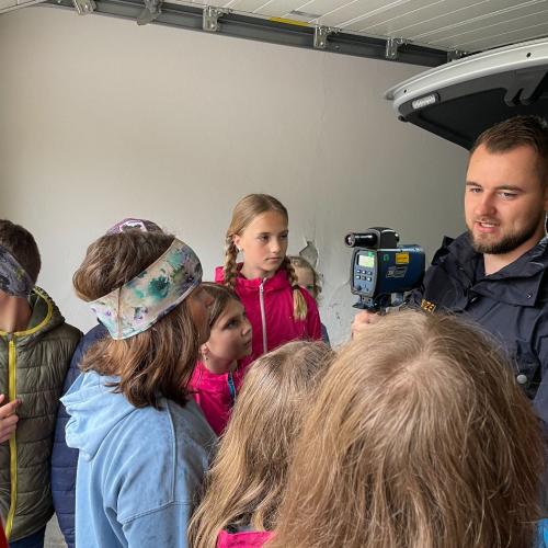 Ein Polizist erklärt den Kindern, wie ein Lasergerät funktioniert.
