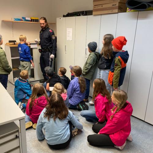 Ein Polizist zeigt den Kindern die Polizeiräumlichkeiten.