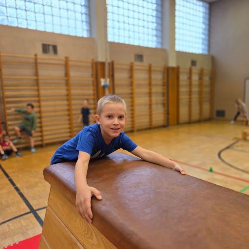 Kinder springen auf den Kasten im Turnsaal.