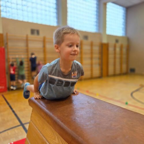 Kinder springen auf den Kasten im Turnsaal.