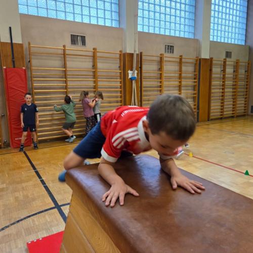 Kinder springen auf den Kasten im Turnsaal.