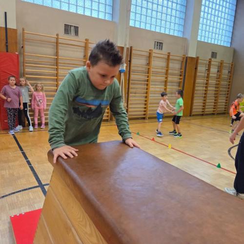 Kinder springen auf den Kasten im Turnsaal.