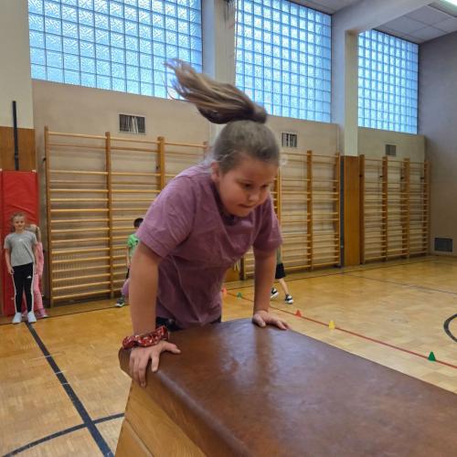 Kinder springen auf den Kasten im Turnsaal.