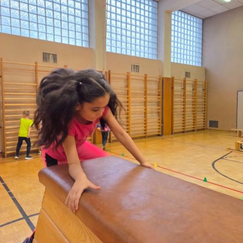 Kinder springen auf den Kasten im Turnsaal.