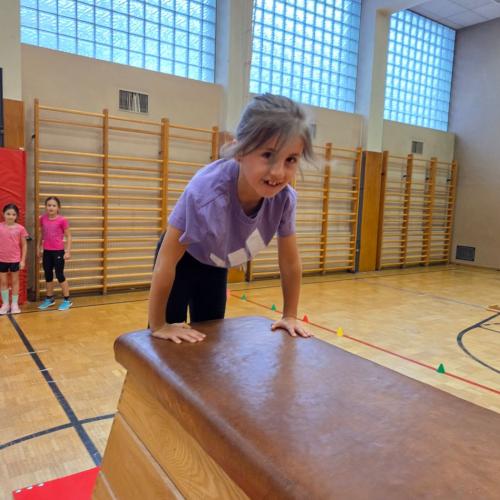 Kinder springen auf den Kasten im Turnsaal.