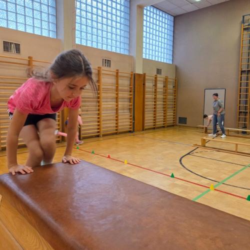 Kinder springen auf den Kasten im Turnsaal.