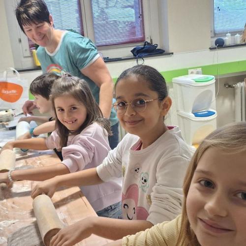 Kinder rollen Keksteig aus.