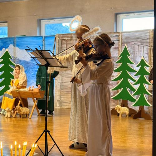 Kinder, als ENgel verkleidet, spielen Geige.