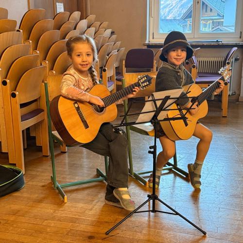 Zwei Kinder spielen Gitarre.