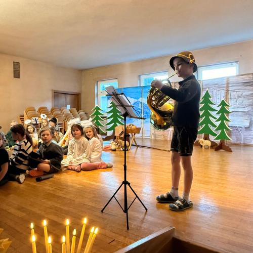 Ein Kind spielt auf einem Horn eine weihnachtliche Melodie.