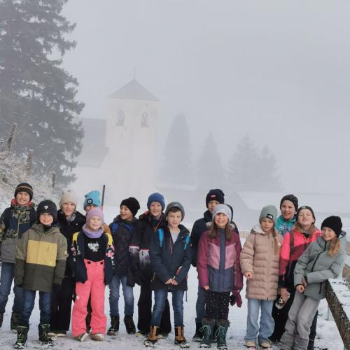 Kinder wandern durch den Schnee zur Nikolauskirche