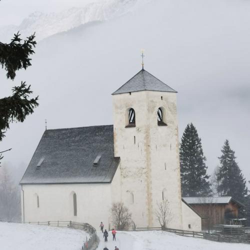 Kinder wandern durch den Schnee zur Nikolauskirche