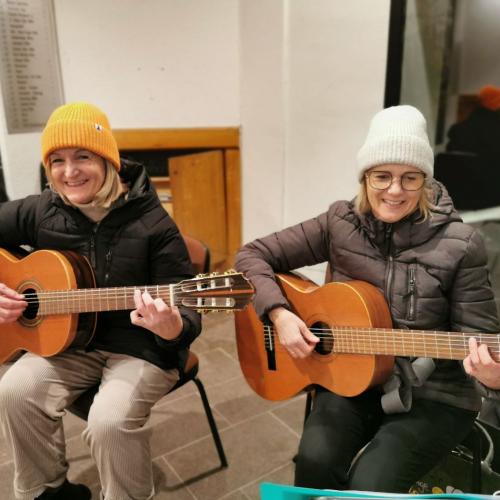 Lehrerinnen spielen Gitarre und begleiten den Schulchor auf dem Adventmarkt