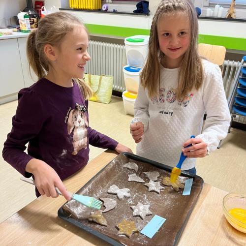 Kinder bestreichen Kekse mit Eigelb.