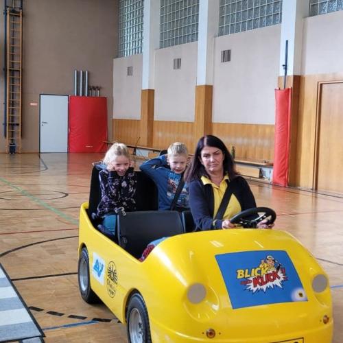 Kinder werden im Blick und Klick - Auto durch den Turnsaal kutschiert.