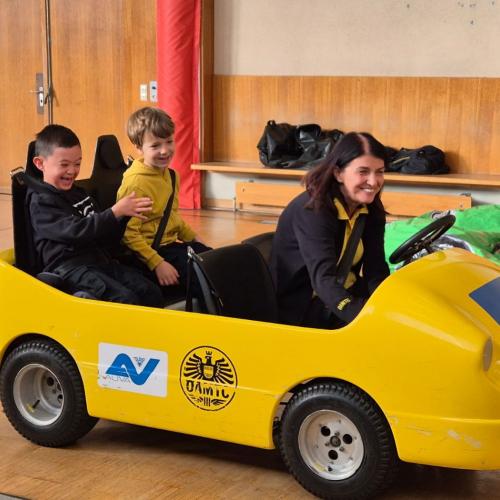 Kinder werden im Blick und Klick - Auto durch den Turnsaal kutschiert.