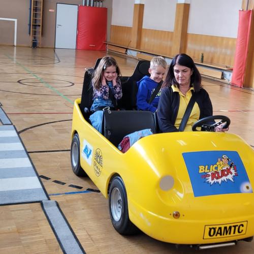Kinder werden im Blick und Klick - Auto durch den Turnsaal kutschiert.