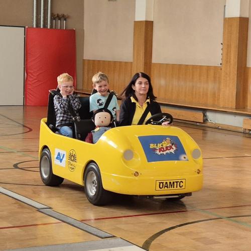 Kinder werden im Blick und Klick - Auto durch den Turnsaal kutschiert.