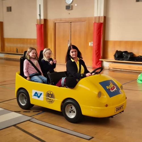 Kinder werden im Blick und Klick - Auto durch den Turnsaal kutschiert.