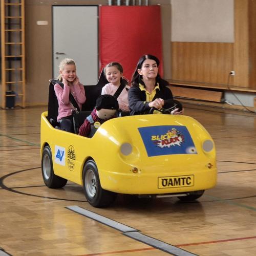 Kinder werden im Blick und Klick - Auto durch den Turnsaal kutschiert.