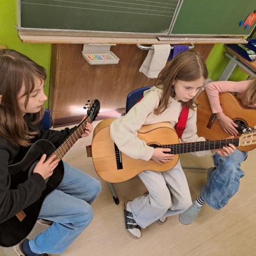 Drei Kinder spielen Gitarre.