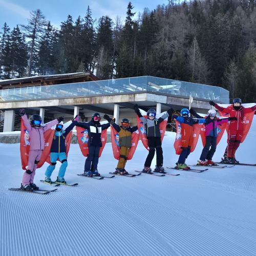 Kinder mit den Werbeflaggen der Schischule als Flügel