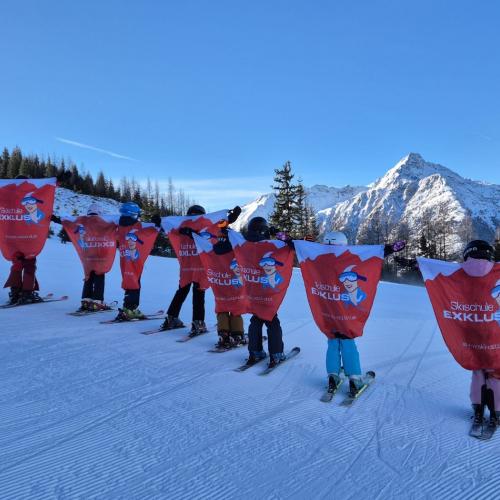 Kinder mit den Werbeflaggen der Schischule als Flügel