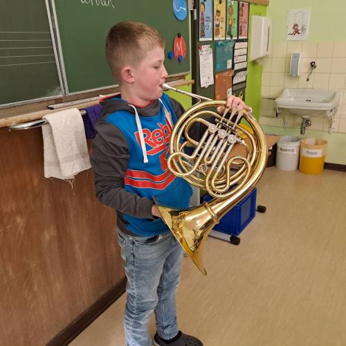 Ein Kind spielt auf dem Horn vor.