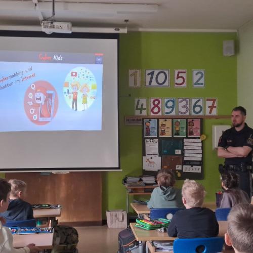 Die Kinder werden von einem Polizist über die Gefahren im Internet aufgeklärt.
