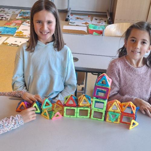Kinder beim Bauen von kleinen Gebäuden mit dem Magnetbaumaterial.