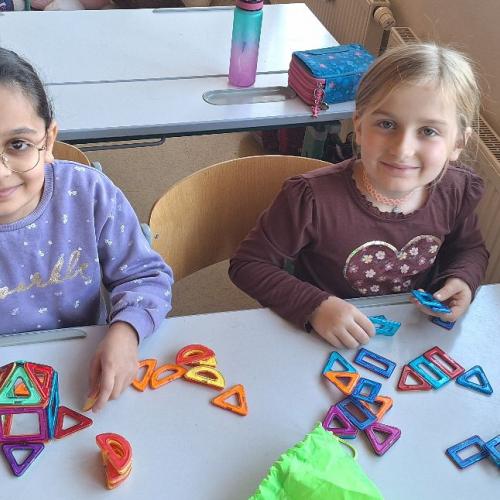Kinder beim Bauen von kleinen Gebäuden mit dem Magnetbaumaterial.