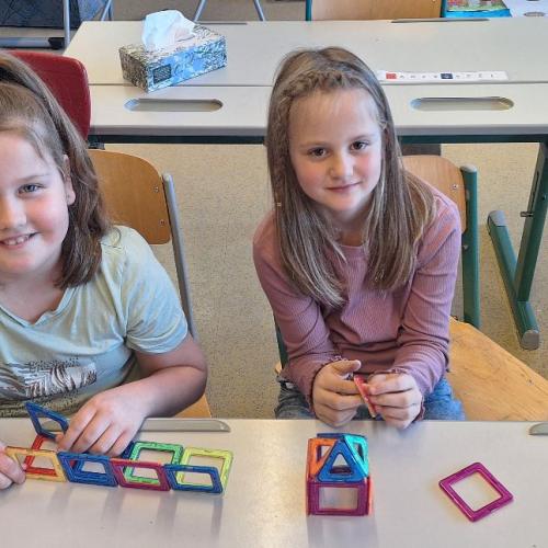 Kinder beim Bauen von kleinen Gebäuden mit dem Magnetbaumaterial.