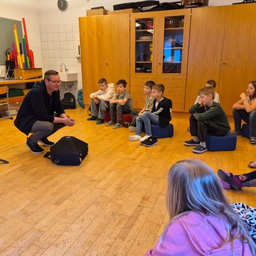 Musikschullehrer erklären den Kindern einiges über Instrumentenkunde.