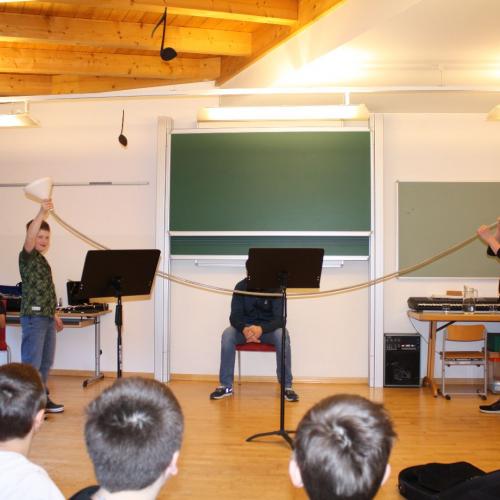 Die Musikschullehrer erklären das Prinzip von Blasinstrumenten.