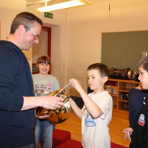 Die Kinder sehen sich das Flügelhorn genauer an.